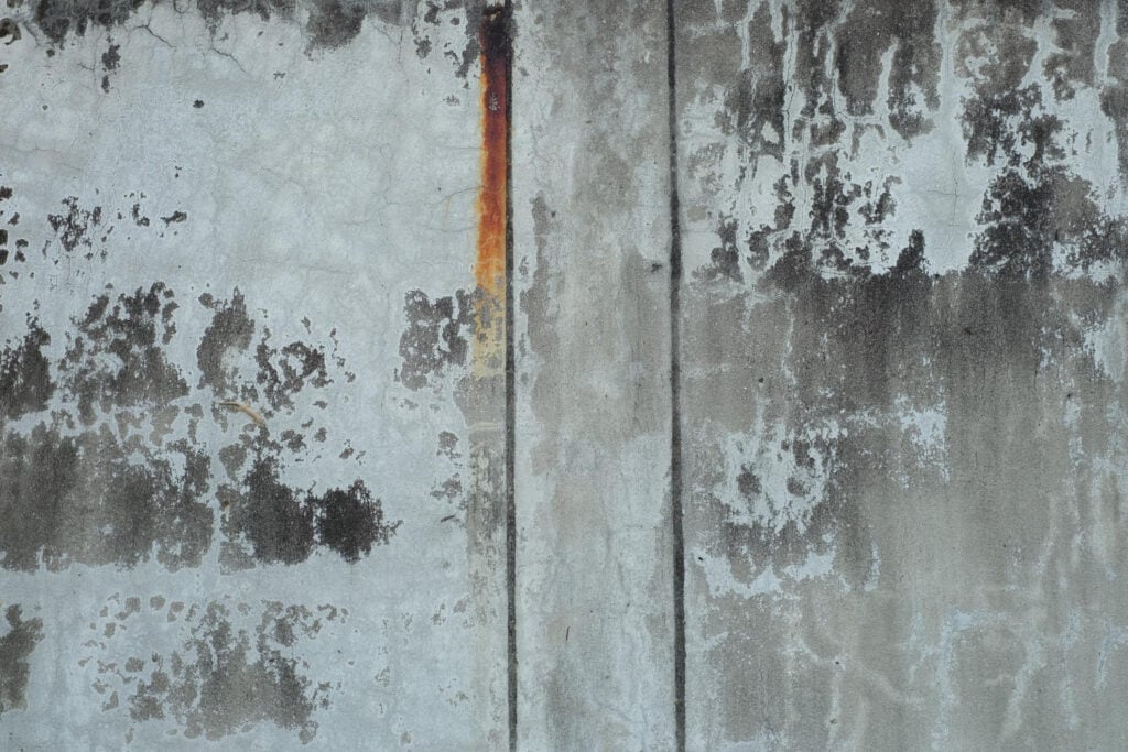 Pressure washing concrete wall in Staffordshire showing removal of dirt and grime.